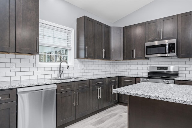 kitchen featuring sink, lofted ceiling, stainless steel appliances, and dark brown cabinets