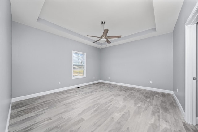 spare room featuring ceiling fan, light hardwood / wood-style floors, and a tray ceiling