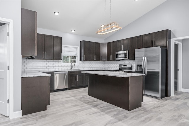 kitchen with appliances with stainless steel finishes, pendant lighting, light hardwood / wood-style floors, and a kitchen island