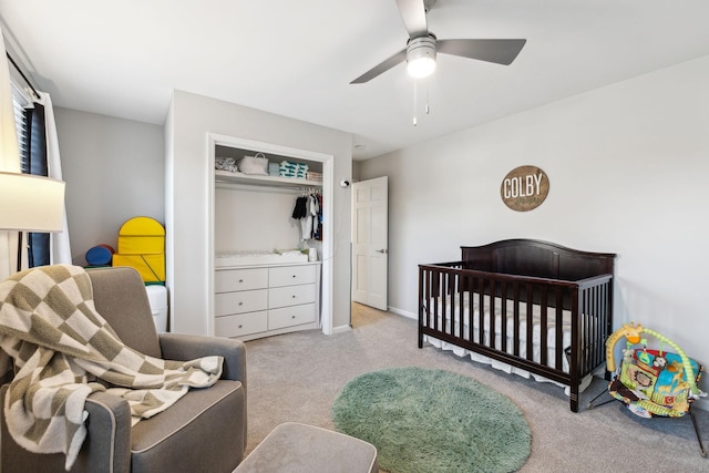 bedroom with ceiling fan, a nursery area, a closet, and light carpet