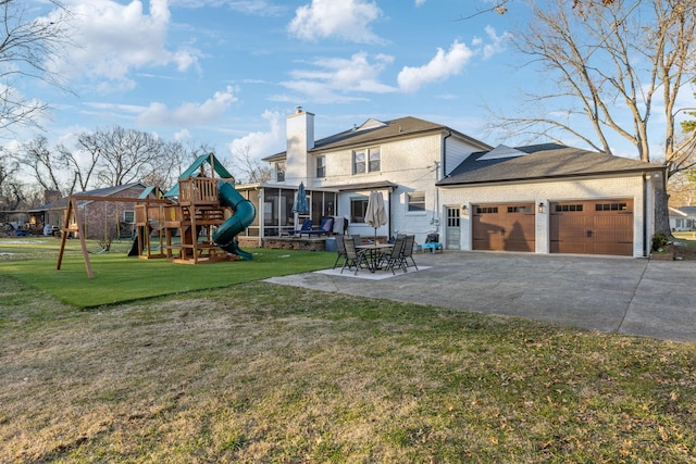 back of property featuring a playground, a garage, a yard, and a patio