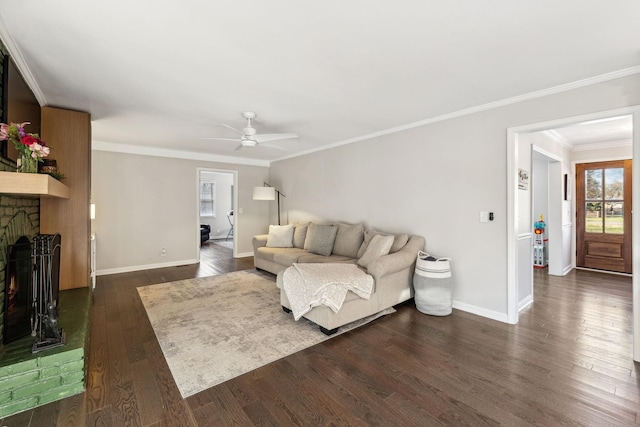 living room with a brick fireplace, crown molding, dark hardwood / wood-style floors, and ceiling fan