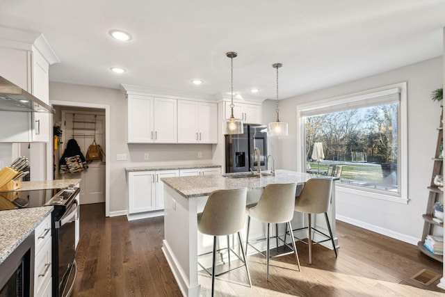 kitchen featuring white cabinetry, pendant lighting, range with electric cooktop, and stainless steel fridge