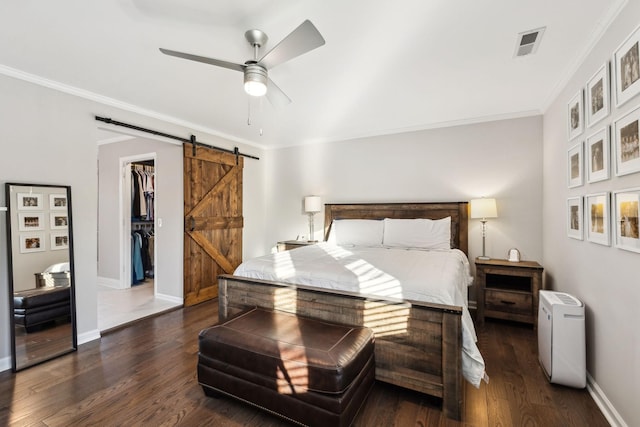 bedroom with a spacious closet, dark hardwood / wood-style flooring, a closet, ceiling fan, and a barn door