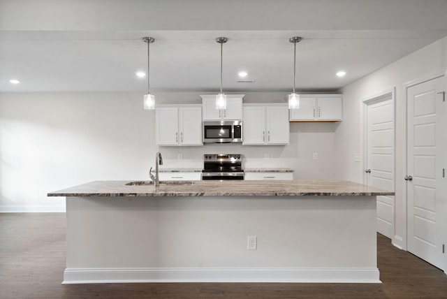 kitchen with sink, appliances with stainless steel finishes, an island with sink, and light stone counters