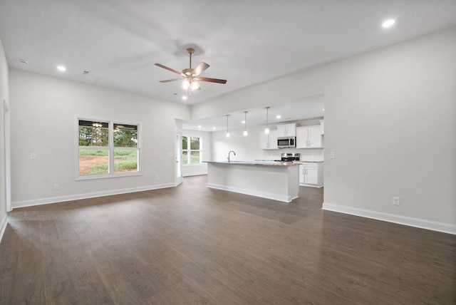 unfurnished living room featuring ceiling fan, dark hardwood / wood-style flooring, and sink