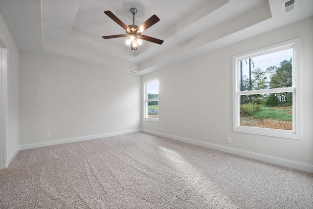 unfurnished room with ceiling fan, carpet, a raised ceiling, and a healthy amount of sunlight