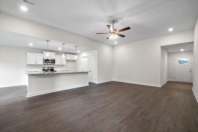 unfurnished living room featuring ceiling fan and dark hardwood / wood-style flooring