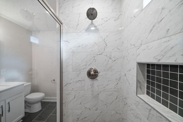 bathroom with tile patterned floors, tiled shower, vanity, and toilet