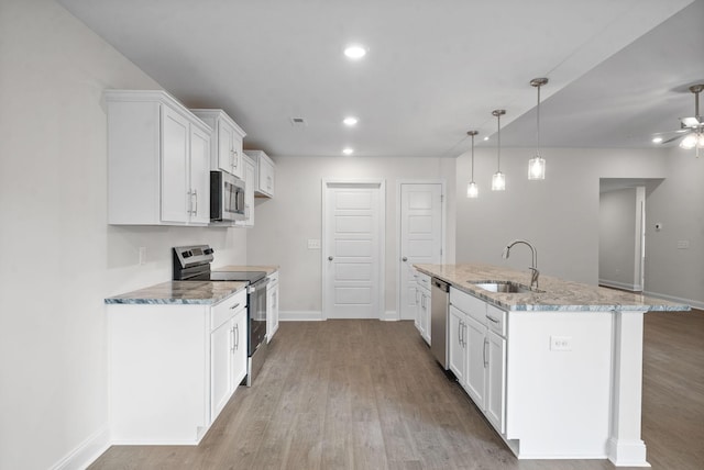 kitchen featuring stainless steel appliances, a kitchen island with sink, hanging light fixtures, white cabinets, and sink