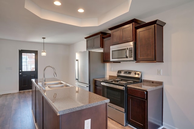 kitchen featuring sink, decorative light fixtures, dark brown cabinets, a center island with sink, and appliances with stainless steel finishes