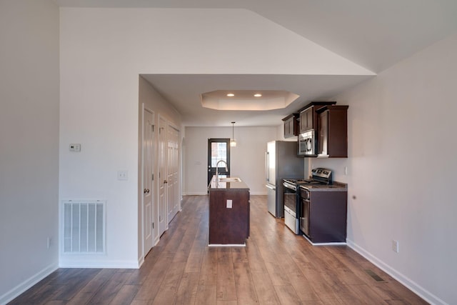 kitchen featuring a raised ceiling, appliances with stainless steel finishes, sink, and dark hardwood / wood-style flooring