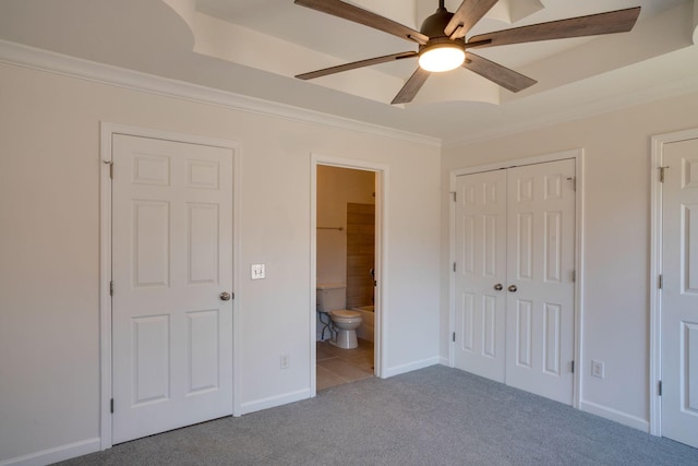 unfurnished bedroom featuring ensuite bath, ornamental molding, carpet floors, a closet, and ceiling fan