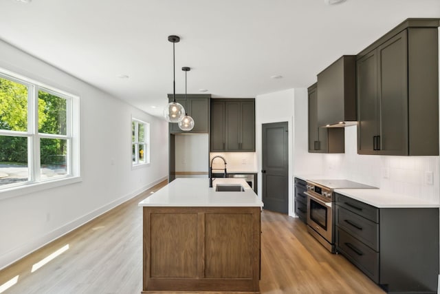 kitchen featuring light wood-type flooring, high end stove, decorative backsplash, and sink