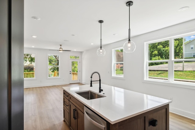 kitchen with an island with sink, ceiling fan, dishwasher, pendant lighting, and sink