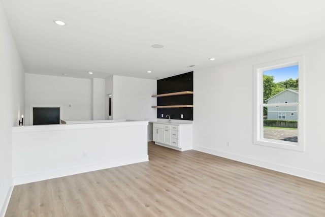 unfurnished living room with sink and light wood-type flooring