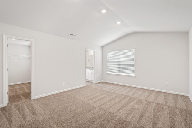 interior space with a spacious closet, lofted ceiling, ensuite bath, a closet, and light colored carpet