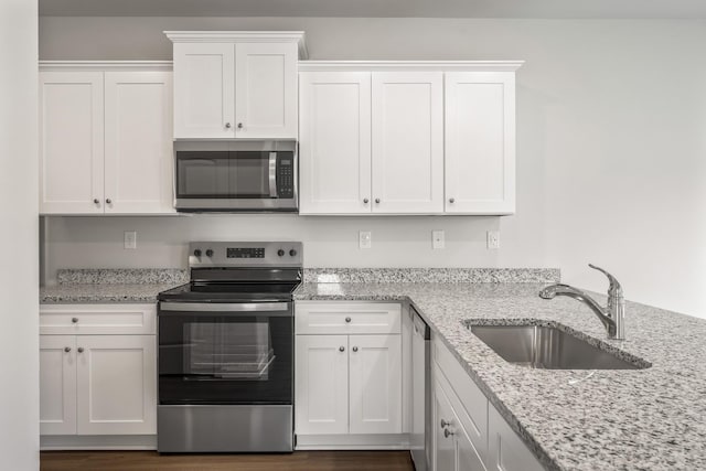 kitchen with light stone countertops, sink, white cabinetry, and appliances with stainless steel finishes