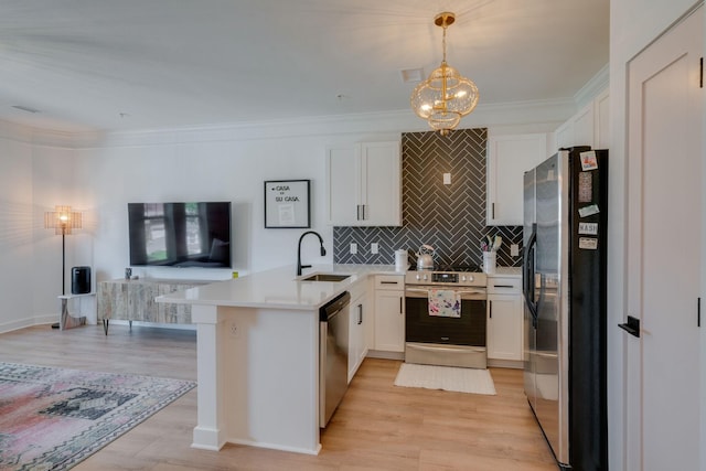 kitchen with kitchen peninsula, sink, white cabinetry, hanging light fixtures, and appliances with stainless steel finishes