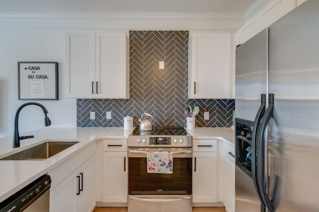 kitchen with white cabinets, appliances with stainless steel finishes, decorative backsplash, sink, and light stone counters