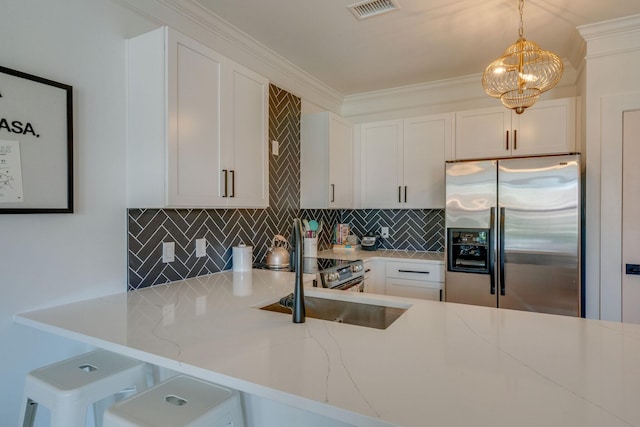 kitchen with stainless steel fridge, backsplash, hanging light fixtures, light stone countertops, and white cabinets