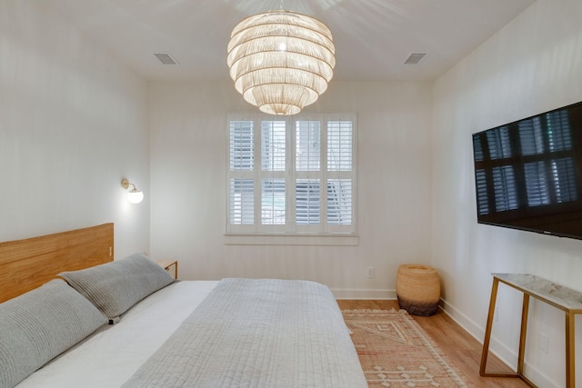 bedroom with wood-type flooring and a notable chandelier