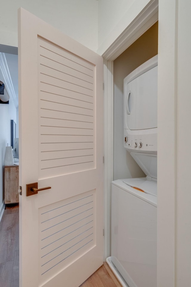 laundry area featuring stacked washer and clothes dryer and hardwood / wood-style floors