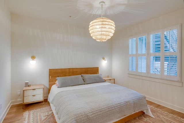 bedroom with light hardwood / wood-style flooring and an inviting chandelier