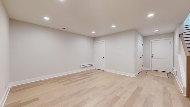 unfurnished room featuring a baseboard radiator and light hardwood / wood-style flooring