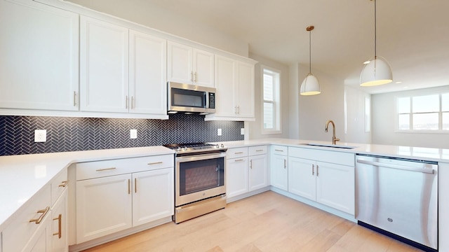 kitchen featuring decorative light fixtures, sink, white cabinetry, and stainless steel appliances