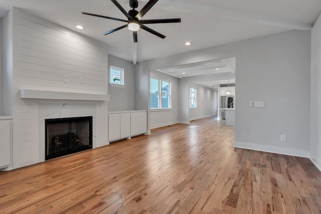 unfurnished living room featuring ceiling fan, light hardwood / wood-style floors, and a fireplace