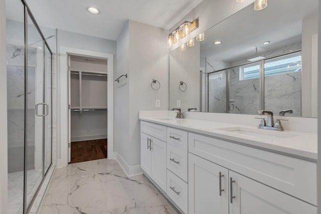 bathroom featuring a shower with shower door and vanity