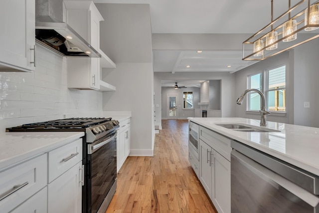 kitchen with white cabinetry, appliances with stainless steel finishes, wall chimney range hood, pendant lighting, and sink