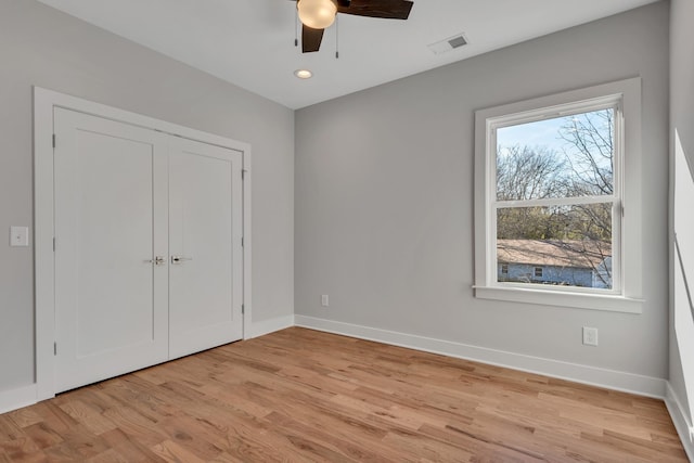 unfurnished bedroom featuring ceiling fan, a closet, light hardwood / wood-style floors, and multiple windows