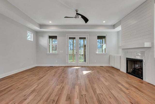 unfurnished living room with ceiling fan, plenty of natural light, light wood-type flooring, and a fireplace