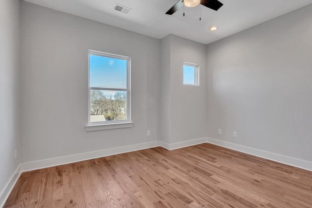 spare room with ceiling fan, a wealth of natural light, and light wood-type flooring