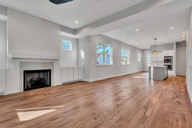 unfurnished living room with light hardwood / wood-style floors, sink, and a fireplace