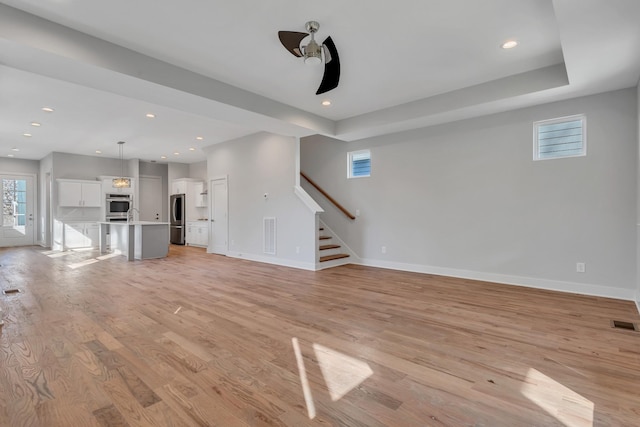 unfurnished living room featuring ceiling fan and light wood-type flooring