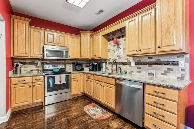 kitchen with light stone counters, backsplash, dark hardwood / wood-style floors, and stainless steel appliances