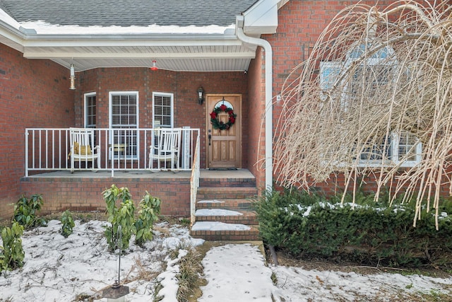 snow covered property entrance featuring covered porch