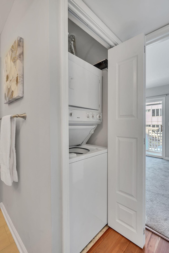 washroom with stacked washer and dryer and light hardwood / wood-style floors