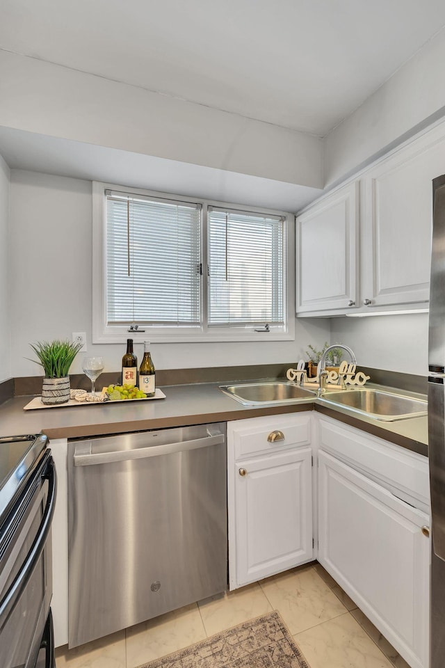 kitchen with stainless steel dishwasher, white cabinetry, plenty of natural light, sink, and light tile patterned floors