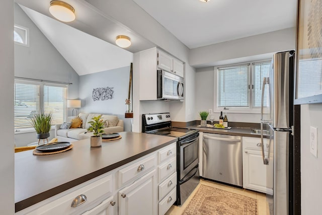 kitchen with white cabinetry, appliances with stainless steel finishes, and lofted ceiling