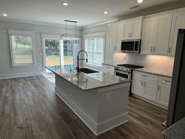 kitchen featuring dark wood-type flooring, white cabinets, stainless steel appliances, and an island with sink