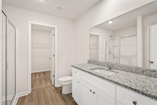 bathroom with wood-type flooring, an enclosed shower, vanity, and toilet