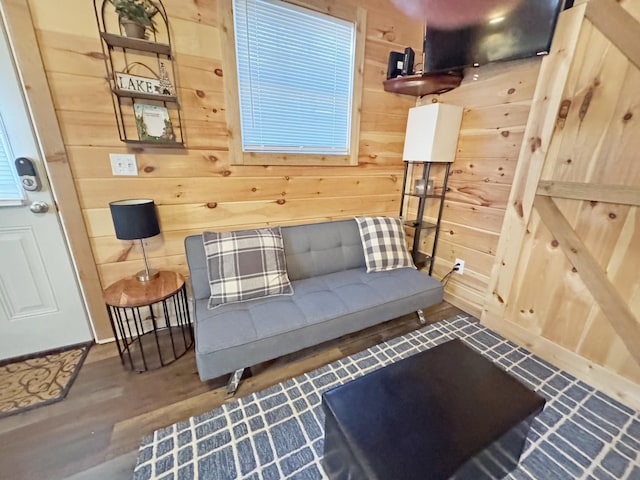 sitting room with hardwood / wood-style floors and wooden walls