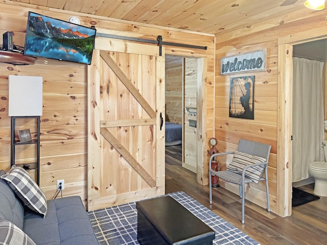 sitting room featuring wooden ceiling, dark hardwood / wood-style floors, wood walls, and a barn door