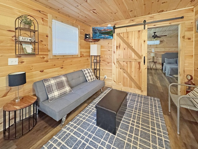 living room with dark wood-type flooring, wooden walls, ceiling fan, wooden ceiling, and a barn door