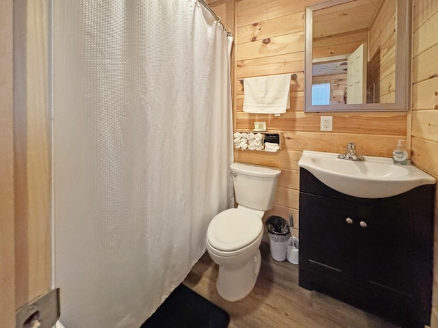 bathroom featuring toilet, vanity, wood walls, and hardwood / wood-style flooring