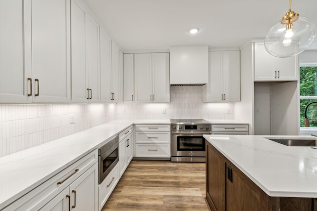 kitchen with decorative light fixtures, sink, white cabinetry, and stainless steel appliances